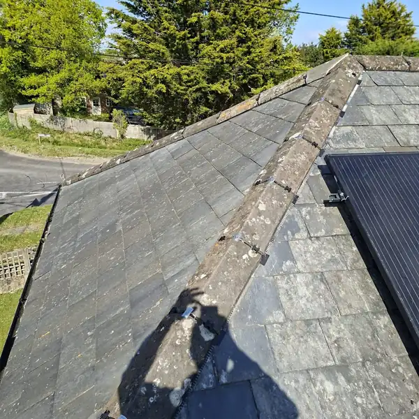 Weathered slate roof hip with worn mortar joints ready for repointing